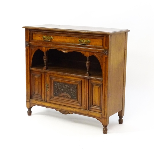 1629 - An Aesthetic movement walnut side cabinet with a chamfered frame and carved floral decoration, the c... 