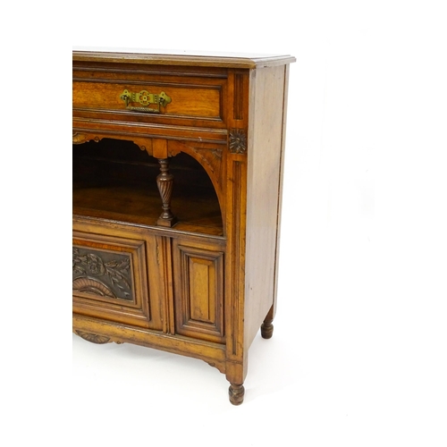 1629 - An Aesthetic movement walnut side cabinet with a chamfered frame and carved floral decoration, the c... 