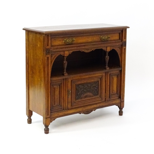 1629 - An Aesthetic movement walnut side cabinet with a chamfered frame and carved floral decoration, the c... 