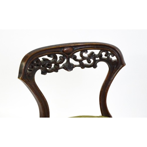 1650 - A mid / late 19thC mahogany nursing chair with a pierced, carved floral top rail above moulded suppo... 