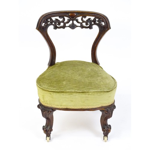 1650 - A mid / late 19thC mahogany nursing chair with a pierced, carved floral top rail above moulded suppo... 