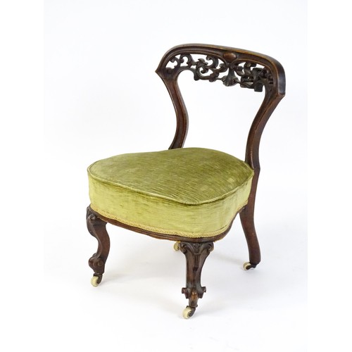 1650 - A mid / late 19thC mahogany nursing chair with a pierced, carved floral top rail above moulded suppo... 