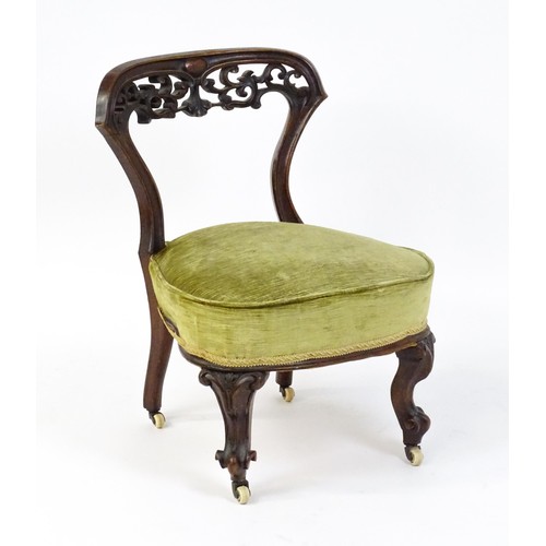 1650 - A mid / late 19thC mahogany nursing chair with a pierced, carved floral top rail above moulded suppo... 