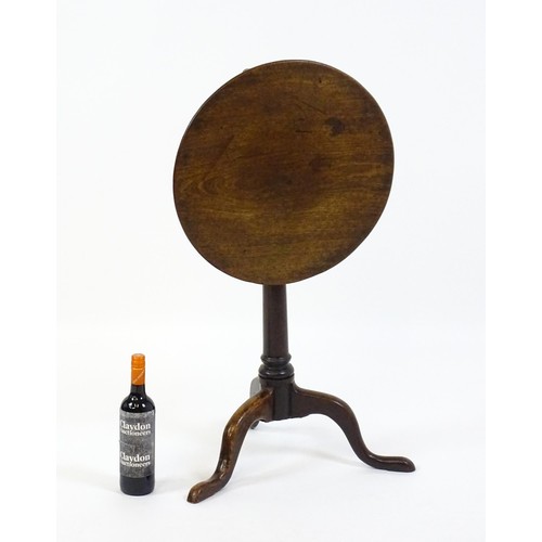 1659 - A late 18thC / early 19thC mahogany tripod table with a circular tilt top above a turned pedestal an... 