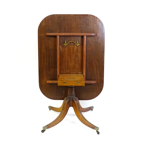 1665 - A late Georgian mahogany tilt top dining table with a ebonised stringing, a turned pedestal and rais... 