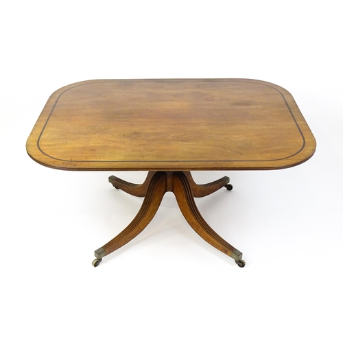 1665 - A late Georgian mahogany tilt top dining table with a ebonised stringing, a turned pedestal and rais... 