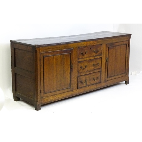 1672 - An 18thC oak dresser with a two plank top above two panelled cupboards and three central drawers wit... 