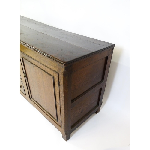 1672 - An 18thC oak dresser with a two plank top above two panelled cupboards and three central drawers wit... 