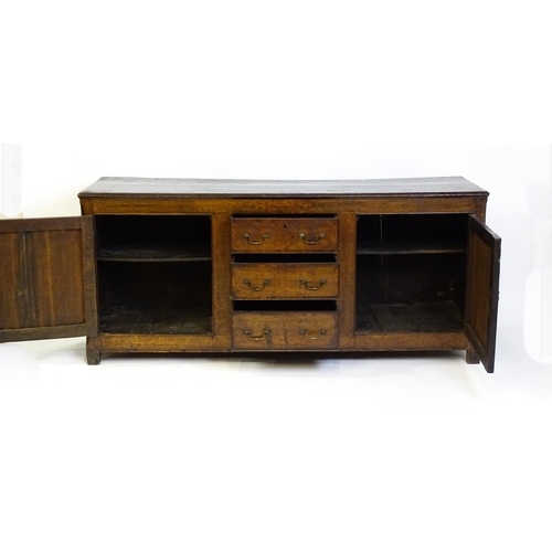 1672 - An 18thC oak dresser with a two plank top above two panelled cupboards and three central drawers wit... 