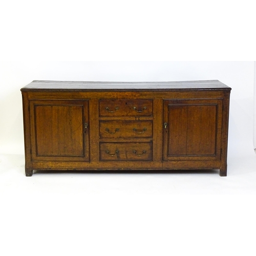 1672 - An 18thC oak dresser with a two plank top above two panelled cupboards and three central drawers wit... 