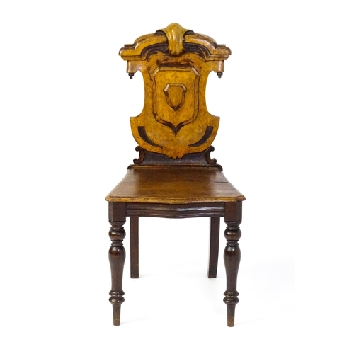 1716 - A Victorian oak shield back hall chair raised on baluster turned front legs and sabre back legs. 17