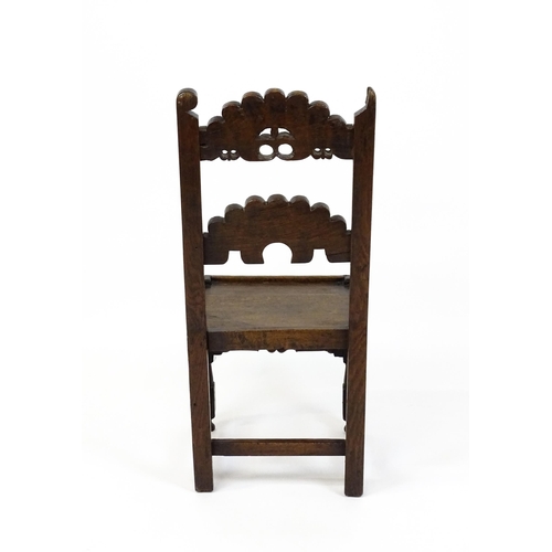 1720 - A 17thC oak peg jointed hall chair / back stool with a carved and scrolled top and mid rail raised o... 