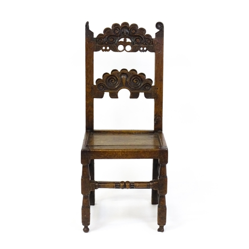 1720 - A 17thC oak peg jointed hall chair / back stool with a carved and scrolled top and mid rail raised o... 