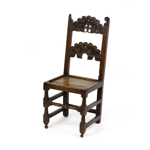 1720 - A 17thC oak peg jointed hall chair / back stool with a carved and scrolled top and mid rail raised o... 