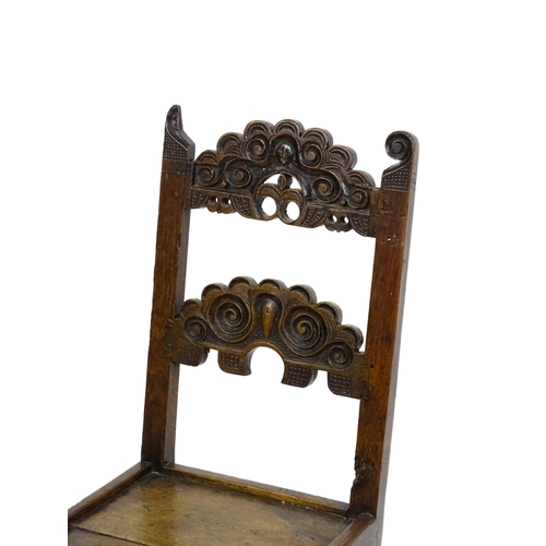 1720 - A 17thC oak peg jointed hall chair / back stool with a carved and scrolled top and mid rail raised o... 