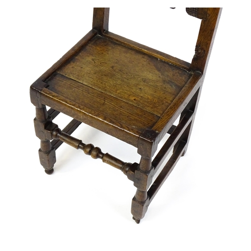 1720 - A 17thC oak peg jointed hall chair / back stool with a carved and scrolled top and mid rail raised o... 