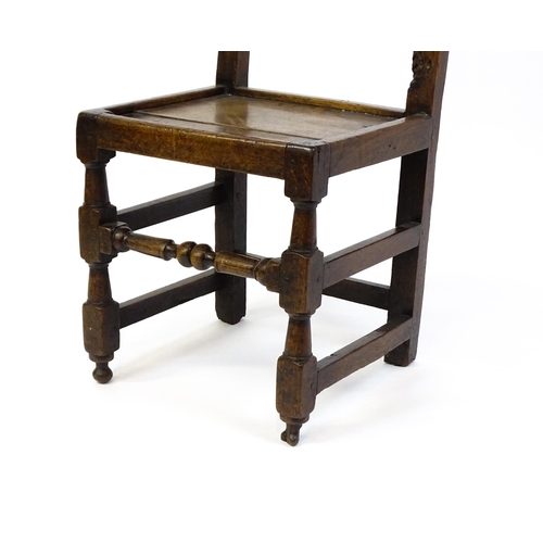 1720 - A 17thC oak peg jointed hall chair / back stool with a carved and scrolled top and mid rail raised o... 