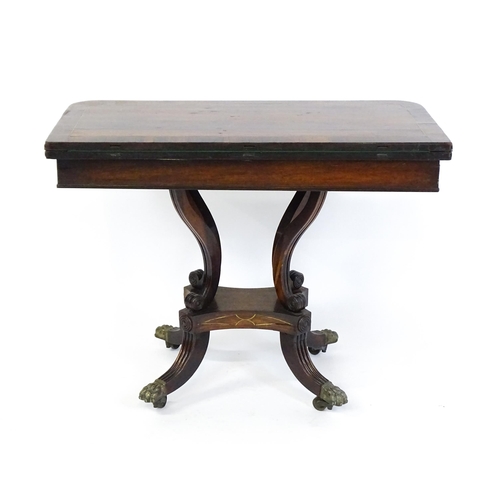 1560 - A Regency rosewood card table with inlaid brass stringing, the revolving top opening to show a baize... 