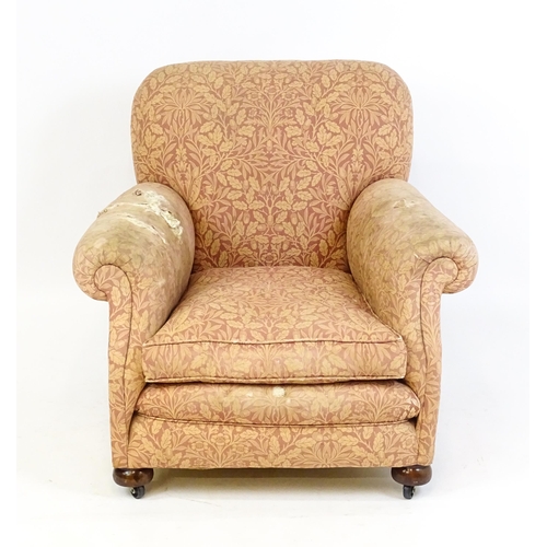 1584 - A late 19thC / early 20thC armchair with scrolled arms and raised on bun feet and castors. 36