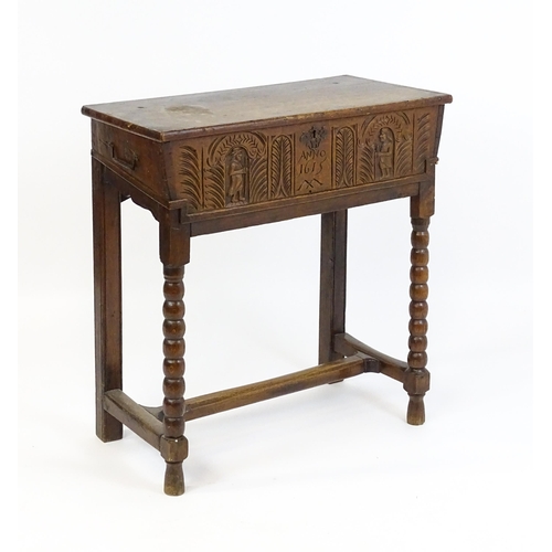 1597 - An 18thC oak box on stand with a carved front panel above a hinged lid, the box raised on four bobbi... 