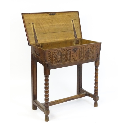 1597 - An 18thC oak box on stand with a carved front panel above a hinged lid, the box raised on four bobbi... 