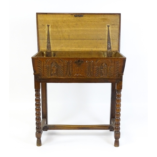 1597 - An 18thC oak box on stand with a carved front panel above a hinged lid, the box raised on four bobbi... 