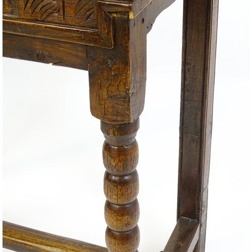 1597 - An 18thC oak box on stand with a carved front panel above a hinged lid, the box raised on four bobbi... 