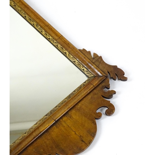 1610 - An early 20thC walnut wall mirror surmounted by a gilt Fleur de Lys, carved scrolled decoration and ... 