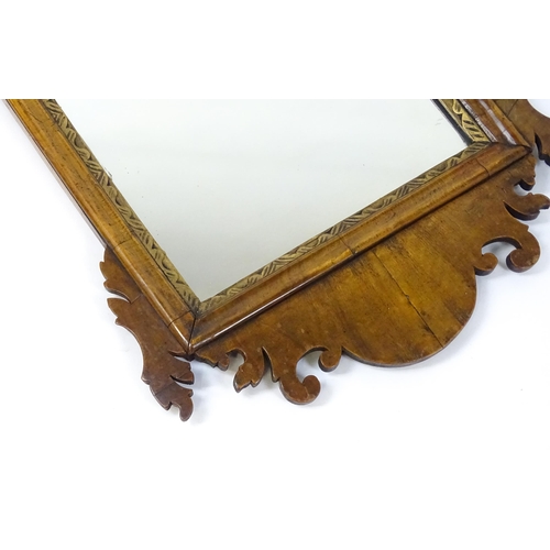 1610 - An early 20thC walnut wall mirror surmounted by a gilt Fleur de Lys, carved scrolled decoration and ... 