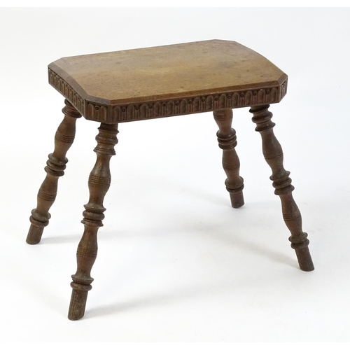 1615 - An early 20thC oak stool with an octagonal canted top and nulled carving and the top raised on four ... 