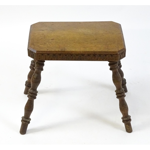 1615 - An early 20thC oak stool with an octagonal canted top and nulled carving and the top raised on four ... 