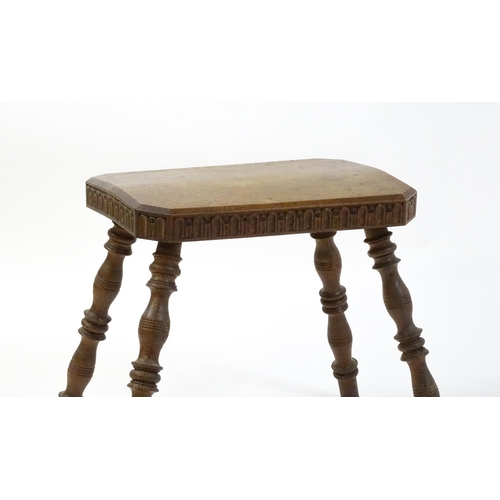 1615 - An early 20thC oak stool with an octagonal canted top and nulled carving and the top raised on four ... 