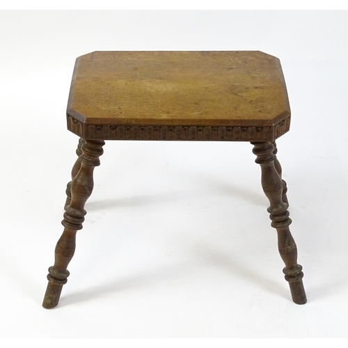 1615 - An early 20thC oak stool with an octagonal canted top and nulled carving and the top raised on four ... 