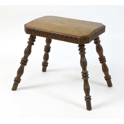 1615 - An early 20thC oak stool with an octagonal canted top and nulled carving and the top raised on four ... 