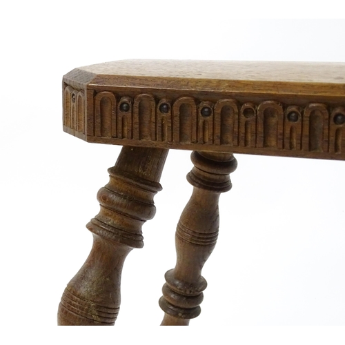 1615 - An early 20thC oak stool with an octagonal canted top and nulled carving and the top raised on four ... 