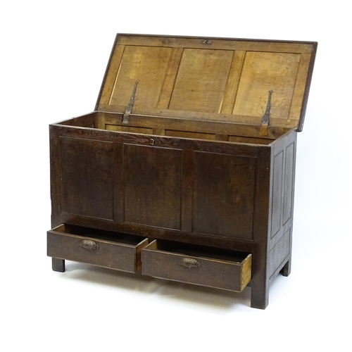 1622 - An early 18thC oak mule chest with a hinged, panelled lid above a panelled front and two short drawe... 