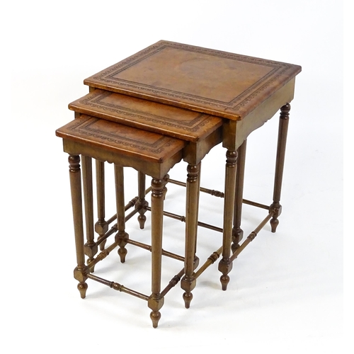 1623 - A mid 20thC nest of three tables with inset leather tops above turned supports united by tapering st... 