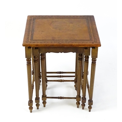 1623 - A mid 20thC nest of three tables with inset leather tops above turned supports united by tapering st... 