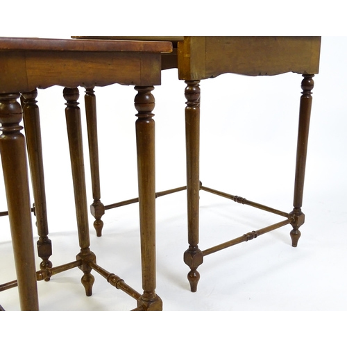 1623 - A mid 20thC nest of three tables with inset leather tops above turned supports united by tapering st... 