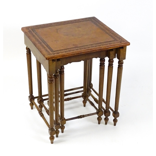 1623 - A mid 20thC nest of three tables with inset leather tops above turned supports united by tapering st... 