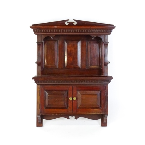 1637 - An early 20thC mahogany wall hanging cabinet with a neo - classical style pediment above a dentil mo... 