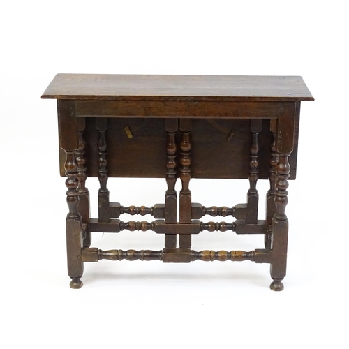 1644 - An 18thC oak gateleg table with a single leaf supported by a double gateleg mechanism formed of bloc... 