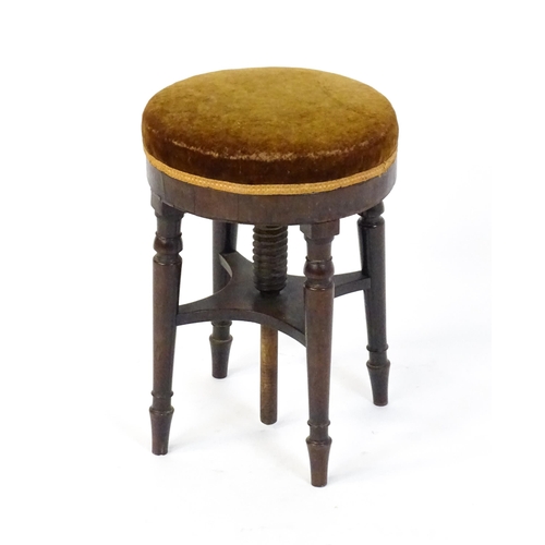 1657 - A 19thC mahogany piano stool with an adjustable upholstered top raised on four turned legs united by... 