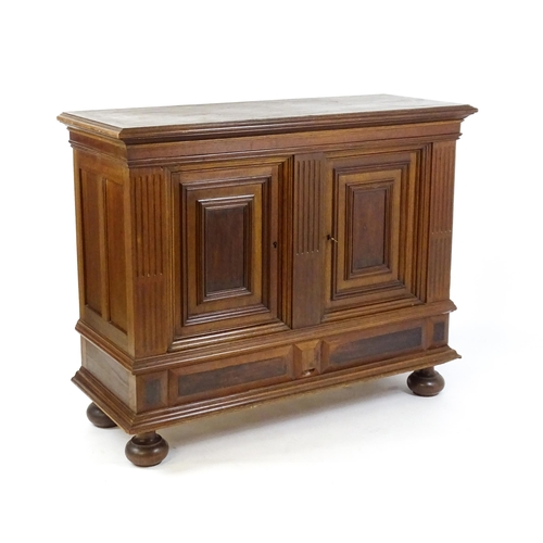 1660 - A late 19thC / early 20thC walnut cupboard with a moulded top above two panelled doors and a fluted ... 