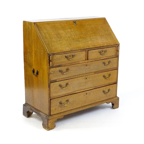 1662 - A Georgian oak bureau with a fall front opening to show crossbanded drawers, a marquetry inlaid door... 