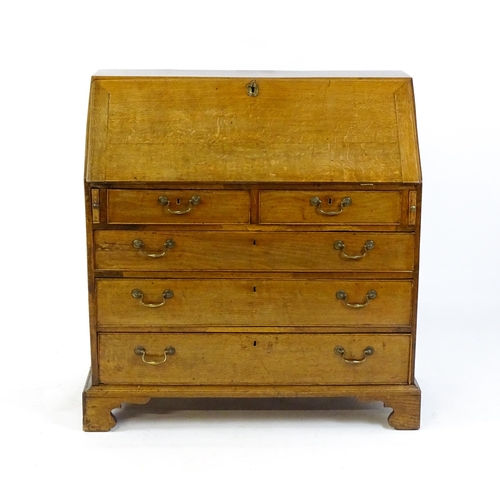 1662 - A Georgian oak bureau with a fall front opening to show crossbanded drawers, a marquetry inlaid door... 