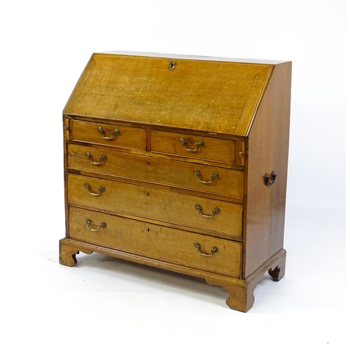 1662 - A Georgian oak bureau with a fall front opening to show crossbanded drawers, a marquetry inlaid door... 