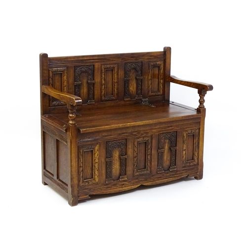 1673 - An early 20thC Old Charm monks bench with a chamfered frame, carved oak panels and a hinged seat. 39... 