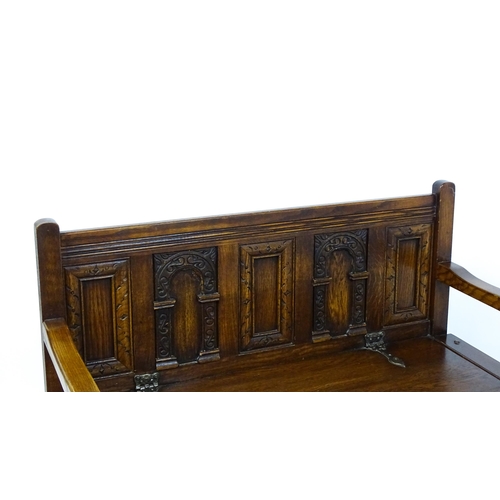 1673 - An early 20thC Old Charm monks bench with a chamfered frame, carved oak panels and a hinged seat. 39... 