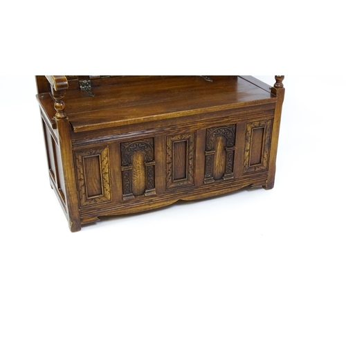 1673 - An early 20thC Old Charm monks bench with a chamfered frame, carved oak panels and a hinged seat. 39... 